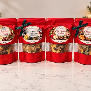 May include: Four red stand-up pouches containing dried fruit and spice simmer pot ingredients. Each pouch features a clear window and a label with the text Rose & Vine Naturals, including Reindeer Treats, Winter Wonderland, Mrs. Claus's Kitchen, and Christmas by the Fire.