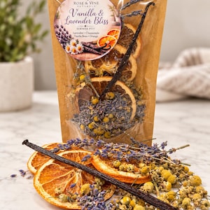May include: A clear stand-up pouch containing dried orange slices, lavender sprigs, chamomile flowers, and a vanilla bean. The label reads Rose & Vine Naturals, Vanilla & Lavender Bliss, Simmer Pot, Lavender, Chamomile, Vanilla Bean, Orange.