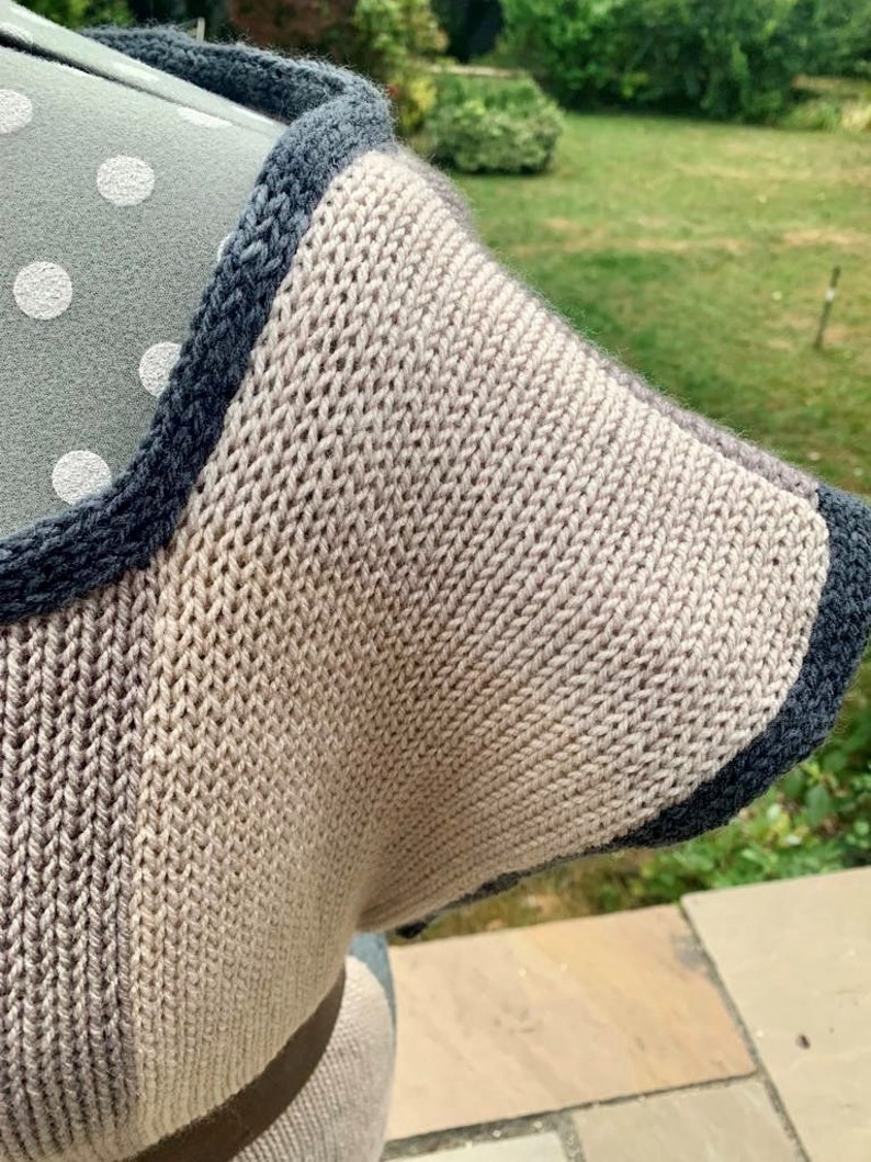 May include: A close-up of a knitted garment with a brown and blue color scheme. The garment has a textured knit pattern and a contrasting blue trim.