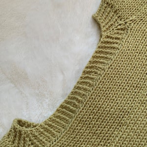 May include: Close-up of a green knitted sweater with a v-neck.
