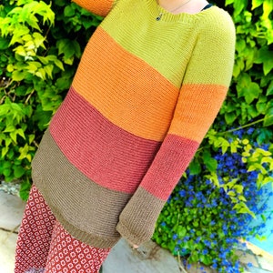 May include: A striped knitted sweater with a brown, red, orange, and green color scheme. The sweater has a relaxed fit and a slightly dropped shoulder.