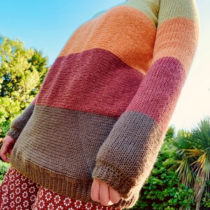 May include: A striped sweater with horizontal bands of green, orange, red, and brown knit wool.