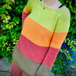 May include: A striped knitted sweater with long sleeves in shades of green, orange, pink, and brown.