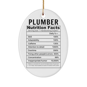 May include: A white oval Christmas bauble with the text "PLUMBER Nutrition Facts" and a table listing various skills and their percentage values. The table includes skills such as "Skill", "Adaptability", "Caffeine", "Attention to detail", "Overtime", "Fixing other people's errors", "Concentration", and "Inappropriate humour".