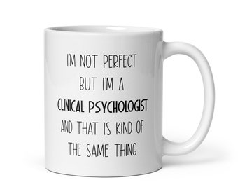 May include: White ceramic coffee mug with black text that reads "I'm not perfect but I'm a clinical psychologist and that is kind of the same thing."
