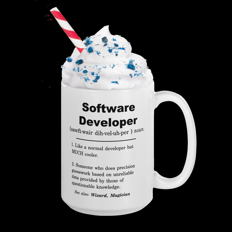 Op de afbeelding: Een witte keramische mok met een zwart-witte definitie van "Softwareontwikkelaar" met een rood-wit gestreepte rietje en slagroom met blauwe sprinkles.