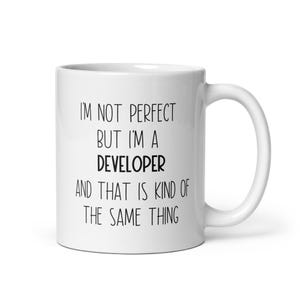 Könnte beinhalten: Eine weiße Keramik-Kaffeetasse mit schwarzem Text, der lautet: "Ich bin nicht perfekt, aber ich bin ein Entwickler, und das ist irgendwie dasselbe."