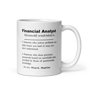 May include: White ceramic mug with a black and white design. The mug features a definition of a "Financial Analyst" with a humorous description. The text reads: "Financial Analyst (fai-nan-shl a-nuh-luhst) n. 1. Someone who solves problems you didn't know you had in ways you don't understand. 2. Someone who does precision guesswork based on unreliable data provided by those of questionable knowledge. See also: Wizard, Magician"