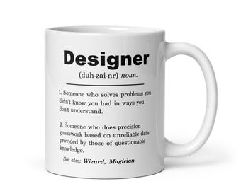May include: White ceramic coffee mug with a black and white design. The mug features the word "Designer" with a definition that reads "Someone who solves problems you didn't know you had in ways you don't understand."