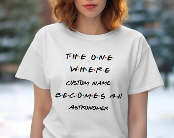 May include: White t-shirt with the text "The One Where [Custom Name] Becomes An Astronomer" in a black font with colorful dots between the letters.