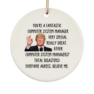 May include: White ceramic ornament with a humorous message about computer system managers. The ornament features a photo of a man with a serious expression and the text "You're a fantastic computer system manager. Very special. Really great. Other computer system managers? Total disasters! Everyone agrees. Believe me."