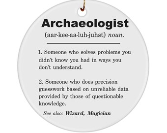 May include: White ceramic ornament with a black and white definition of the word "Archaeologist" with the pronunciation and a humorous definition. The definition reads: "Someone who solves problems you didn't know you had in ways you don't understand. Someone who does precision guesswork based on unreliable data provided by those of questionable knowledge."  The ornament also includes the text "See also: Wizard, Magician."