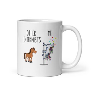 Könnte beinhalten: Weiße Keramiktasse mit einer lustigen Grafik, die andere Internisten mit einem Pferd und den Benutzer mit einem Einhorn auf einer Stange vergleicht. Der Text lautet "Andere Internisten" und "Ich".