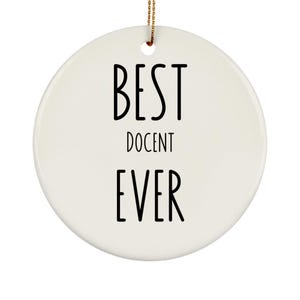May include: A round, white ceramic ornament with the words "BEST DOCENT EVER" in black, bold letters. The ornament has a small hole at the top with a gold string for hanging.