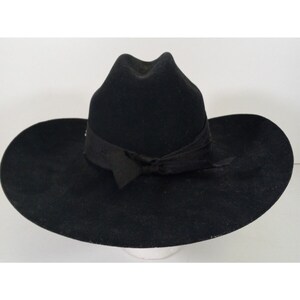 Pode incluir: Um chapéu de cowboy de feltro preto com uma aba larga e uma fita preta.