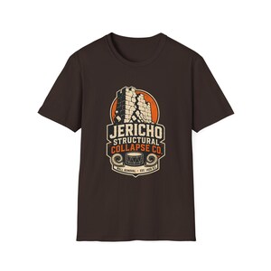 Puede incluir: Una camiseta de manga corta de color marrón oscuro con un estampado gráfico de un muro de piedra en ruinas. El texto dice JERICHO STRUCTURAL COLLAPSE CO. WALL REMOVAL EST. 1406 B.C. con una ilustración de un tambor y dos cuernos de carnero.