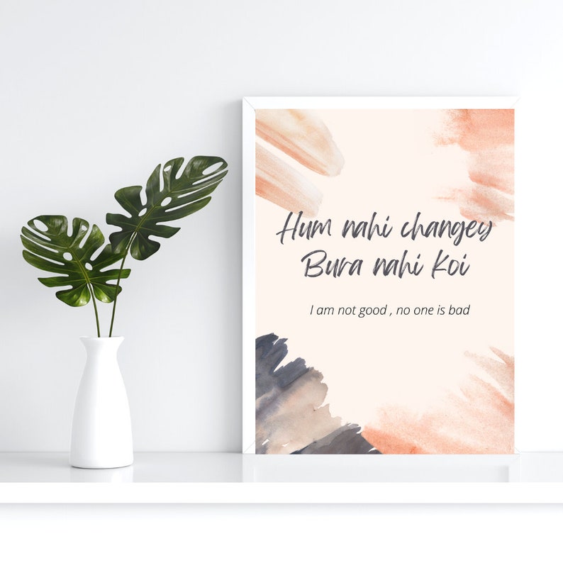 K&ouml;nnte beinhalten: Ein wei&szlig;er gerahmter Druck mit einem Pfirsichhintergrund und abstrakten Aquarellformen in den Farben Pfirsich, Grau und Braun. Der Druck zeigt den Text "Hum nahi changey Bura nahi koi" in grauer Kursivschrift und den Text "I am not good, no one is bad" in kleinerer grauer Schrift.