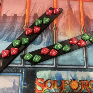 May include: Two black trays with a red and green dice on each. The trays have the words "SOLFORGE FUSION" and "KH" printed on them.