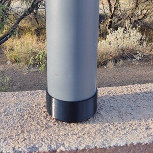 Pu&ograve; includere: Un palo di metallo grigio con una base di plastica nera. Il palo &egrave; su una superficie di cemento.