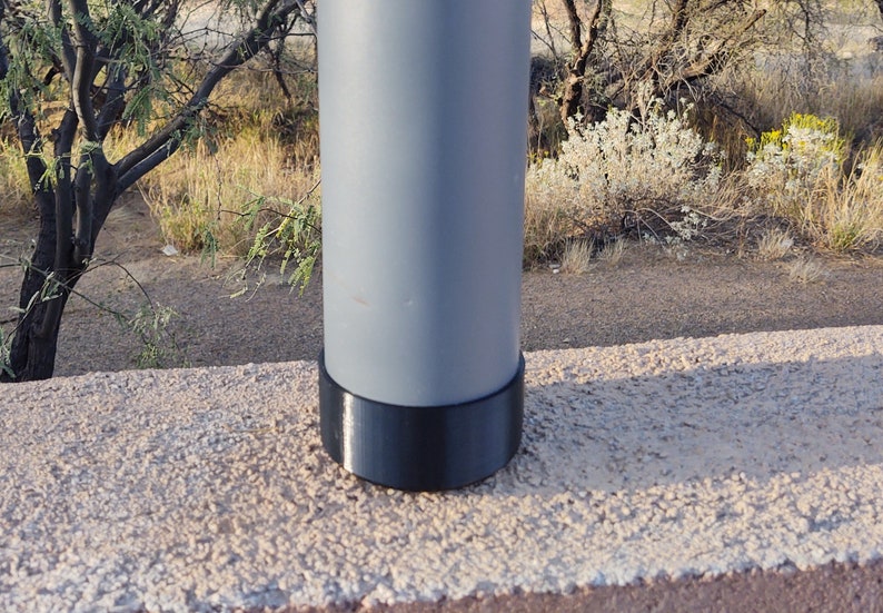 Pu&ograve; includere: Un palo di metallo grigio con una base di plastica nera. Il palo &egrave; su una superficie di cemento.