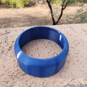 Pu&ograve; includere: Un anello di plastica blu, probabilmente un giocattolo o parte di un oggetto pi&ugrave; grande.