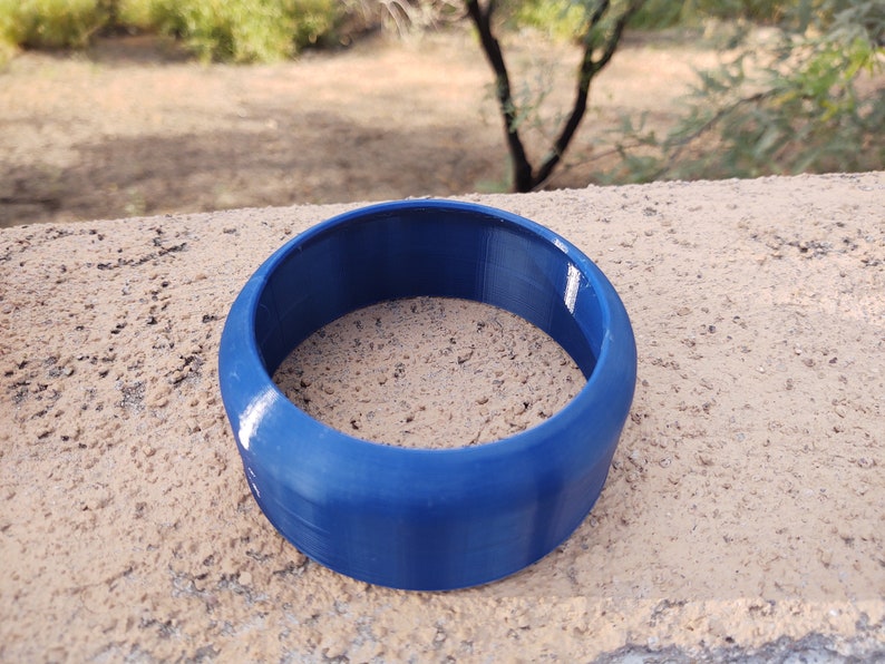 Pu&ograve; includere: Un anello di plastica blu, probabilmente un giocattolo o parte di un oggetto pi&ugrave; grande.