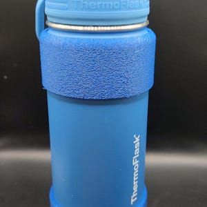 Pu&ograve; includere: Una bottiglia d'acqua blu con un tappo blu e un logo "ThermoFlask" bianco sul lato.