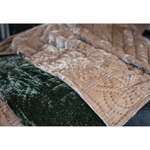 May include: Two quilted velvet throw blankets, one in a deep green color and the other in a light brown color. The blankets are folded and layered on top of each other.