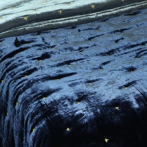 May include: A navy blue velvet quilt with gold star embroidery. The quilt is quilted in a diamond pattern.