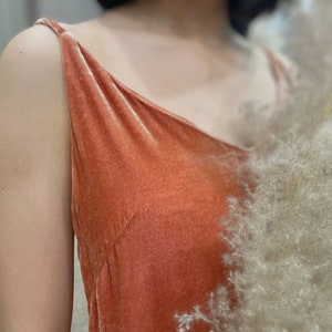 Può includere: Primo piano di un top a spalline in velluto color corallo. Il tessuto ha una texture morbida e lussuosa.