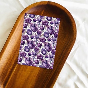 May include: A purple floral print on a white background. The print features a repeating pattern of purple tulips.