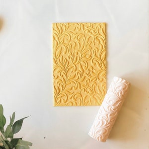 May include: A yellow silicone rolling pin with a floral design, and a matching silicone sheet with the same design.