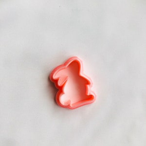 Puede incluir: Un cortador de galletas de plástico rosa con forma de conejo.