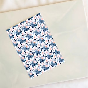 May include: A white sheet of paper with a repeating pattern of blue and pink flowers. The flowers are watercolor style and have a soft, romantic feel.