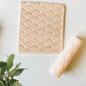 May include: A beige silicone rolling pin and a beige silicone mat with a chevron pattern. Both tools are used for creating decorative patterns on fondant or clay.