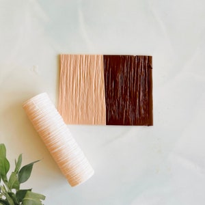 May include: A white textured roller and a silicone sheet with two different wood grain patterns, one in brown and one in peach.