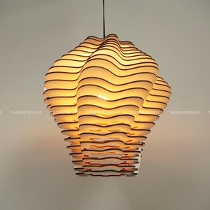 May include: A white, layered, wooden pendant light fixture with a warm, yellow glow. The light fixture is shaped like a cloud and has a modern, minimalist design.