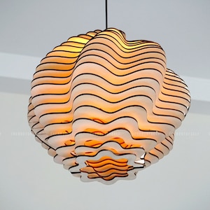 Könnte beinhalten: Eine mehrstufige weiße und braune Hängelampe mit wellenförmigem Design. Die Lampe ist eingeschaltet und strahlt ein warmes gelbes Licht aus.