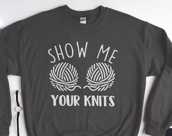 Puede incluir: Una sudadera gris oscuro con el texto "Show Me Your Knits" en blanco. El texto está acompañado por un gráfico de dos ovillos de lana.