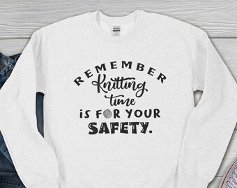 May include: White long-sleeved sweatshirt with black text that reads "Remember Knitting Time is for Your Safety."