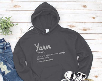 May include: A dark gray hooded sweatshirt with the word "Yarn" defined as "An item to which the word enough does not apply. See also still not enough."