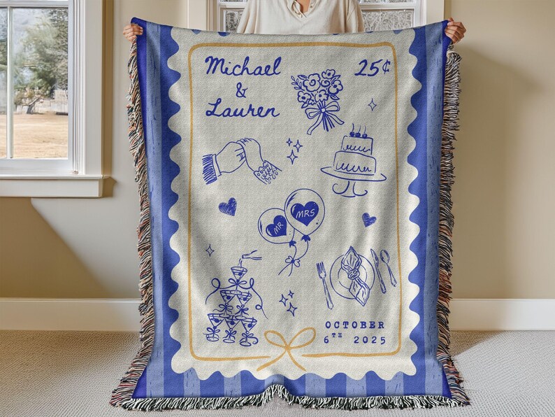 May include: A woven throw blanket with a blue and cream design. The blanket features a blue border and a cream-coloured centre with blue illustrations of wedding-related elements, including a cake, balloons, and the date October 6th, 2025.