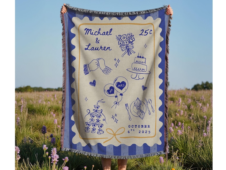 May include: A beige and blue woven blanket with a wedding design. The blanket features illustrations of a bouquet, cake, champagne glasses, and balloons. The names "Michael & Lauren" and the date "October 6th 2025" are also displayed.