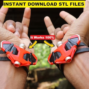 Könnte beinhalten: Ein Paar rote und schwarze Web-Shooter, die wie Armbänder an den Handgelenken getragen werden, mit dem Text "It Works 100%" darüber.