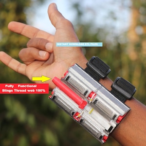 May include: A wrist-mounted web shooter device featuring a clear plastic housing, a red cylindrical component, and black adjustable hook-and-loop straps. Text on the device reads: INSTANT DOWNLOAD STL FILES and Fully Functional Slings Thread web 100%.