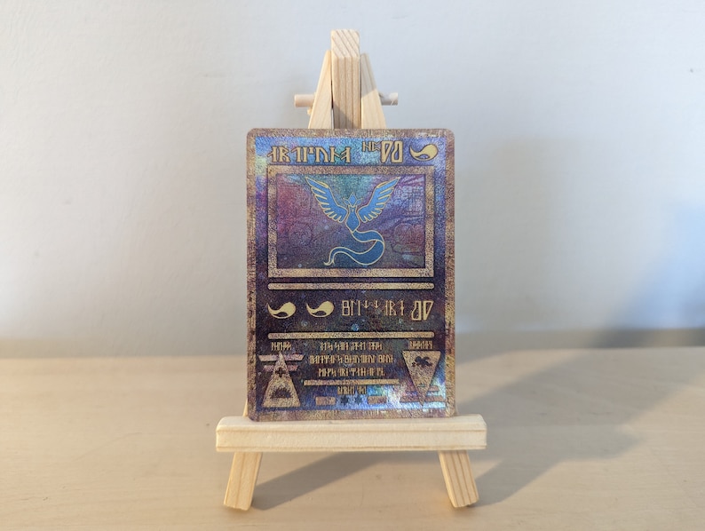 Pode incluir: Um cart&atilde;o de Pok&eacute;mon hologr&aacute;fico com uma imagem azul e dourada do Pok&eacute;mon Ho-Oh. O cart&atilde;o tem um fundo dourado com uma borda preta e o texto "Ho-Oh" em letras douradas.