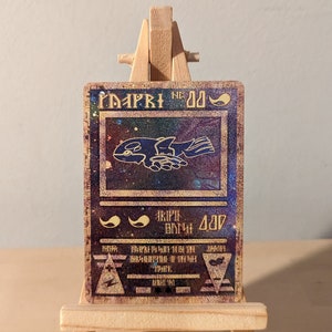May include: A holographic trading card with a blue and purple background. The card features a black and white illustration of a creature with wings and a text box that reads "MAPPY NE 00".