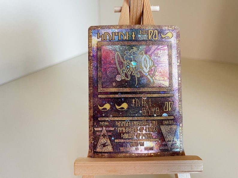 May include: A holographic trading card with a gold and purple background. The card features a holographic image of a creature with a blue eye. The card text reads "DARK" and "ATK 2000 DEF 2000".