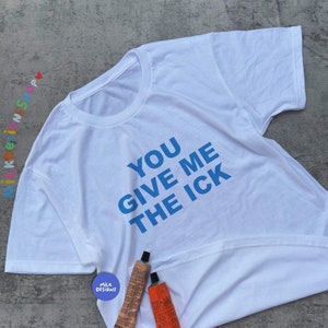 May include: White t-shirt with blue text that reads "You Give Me The Ick".