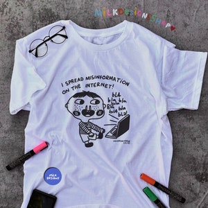 May include: White t-shirt with a black and white illustration of a person sitting at a laptop with the text "I spread misinformation on the internet!" and "bla bla bla bla bla bla!" printed on the front.